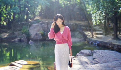 Portrait of young woman standing against trees