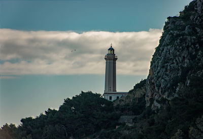 Lighthouse by sea against sky