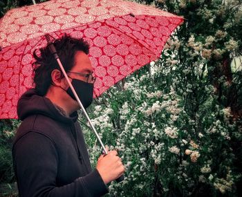 Midsection of man holding umbrella standing in rain