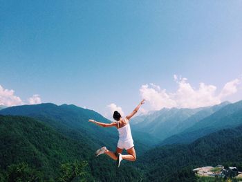 Rear view of woman jumping on landscape