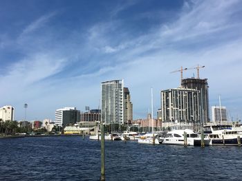 Sailboats in sea by modern buildings against sky in city