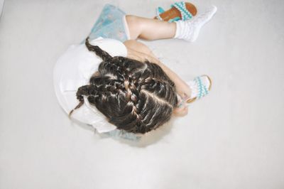 Directly above shot of girl wearing shoe while sitting at home