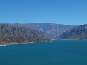 Scenic view of sea and mountains against clear blue sky