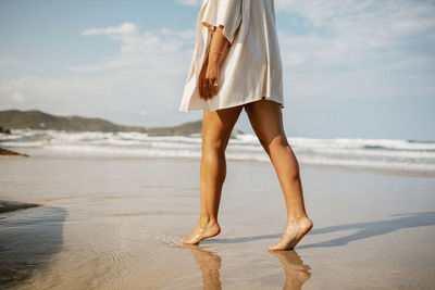 Low section of woman standing at beach