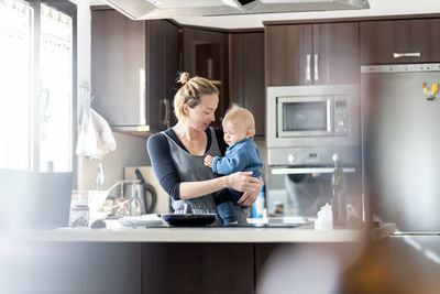 Side view of young woman using mobile phone while sitting at home