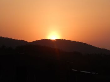 Scenic view of silhouette mountains against orange sky