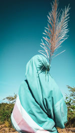 Person covered in textile standing on field against clear blue sky
