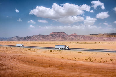 Trucks on desert against sky