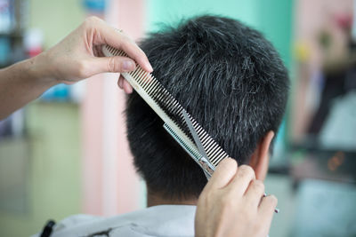 Close-up of barber cutting hair of man at shop