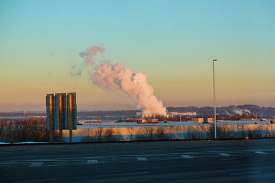 Smoke emitting from factory against sky during sunset