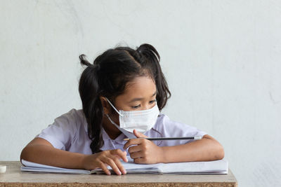 Cute girl wearing mask studying at school