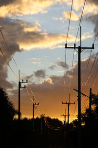 Low angle view of electricity pylon against sky during sunset