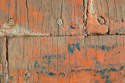 Close up shot of old orange paint texture peeling off wood plank background