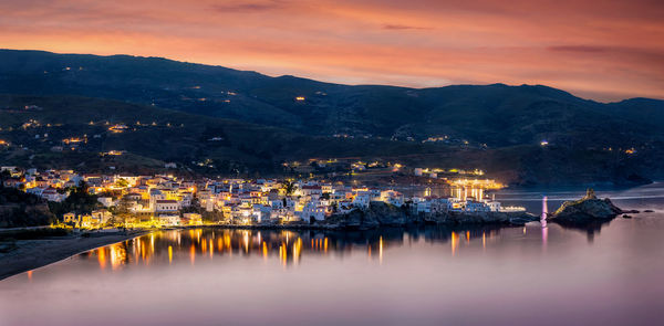 Illuminated buildings in town against sky during sunset