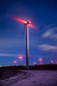 Wind turbines on field against sky at night