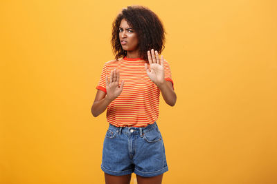 Young woman standing against orange background