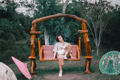 Portrait of smiling young woman sitting against plants