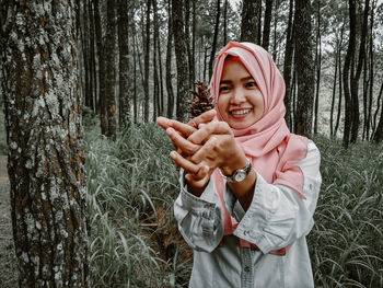 Portrait of woman holding pine cone in forest