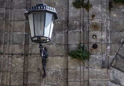 Electric lamp on street against wall