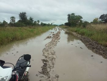 Road by canal against sky