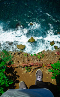 Low section of person standing by sea