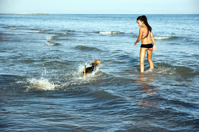 Happy girl with afro hairstyle, playing with a dog on the beach person