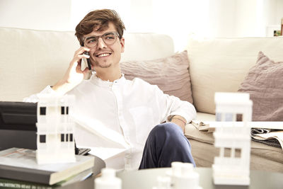 Young man using mobile phone while sitting on sofa