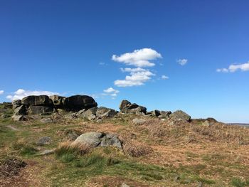 Scenic view of rocks on field against blue sky