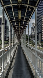 Empty bridge amidst buildings in city