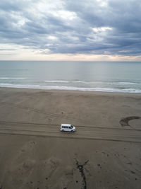 Van driving a long infinite sandy road