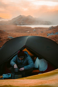 Portrait of man relaxing on land against sky during sunset