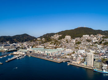 Aerial view of town by sea against clear blue sky