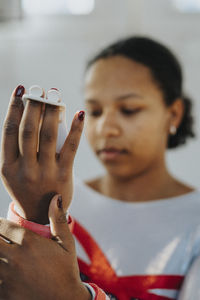 Female athlete adjusting protection band while standing in gym