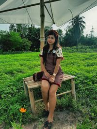 Portrait of young woman sitting on field