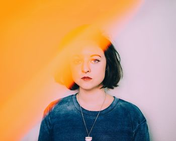 Portrait of confident young woman standing against wall