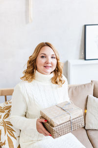 Portrait of smiling young woman sitting on sofa