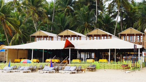 Built structure on beach by palm trees against clear sky