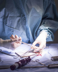 Cropped hands of surgeon holding medical equipment in operating room