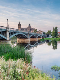 Arch bridge over river against cloudy sky