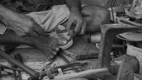 Low section of cobbler sewing sandal at workshop