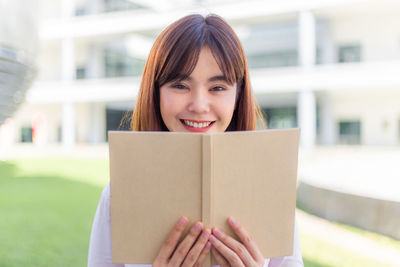 Portrait of a smiling young woman holding book