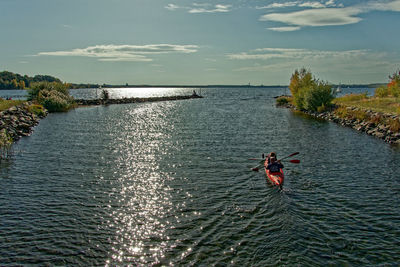 Rear view of man in sea against sky