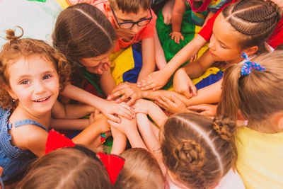 High angle view of kids stacking hands outdoors