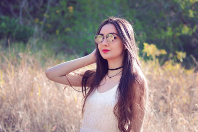 Portrait of young woman in sunglasses against trees