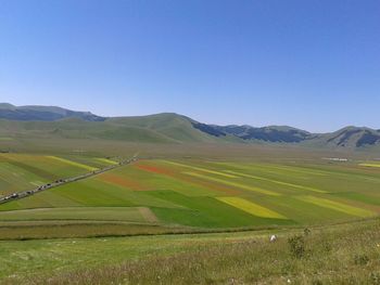 Scenic view of farm landscape against clear blue sky