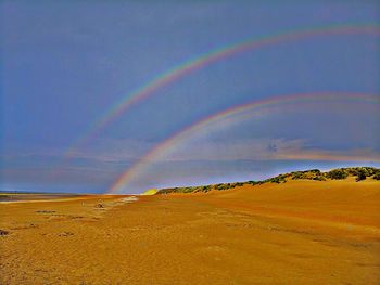 Scenic view of rainbow over sea against sky