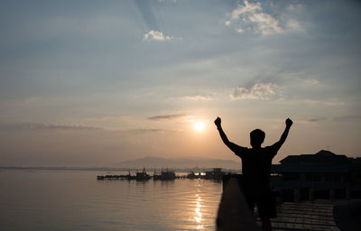 Man standing by sea against sky during sunset