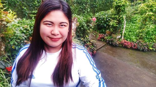 Portrait of smiling young woman against plants