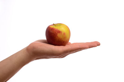 Close-up of hand holding apple against white background