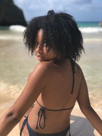 Portrait of woman in bikini sitting at beach